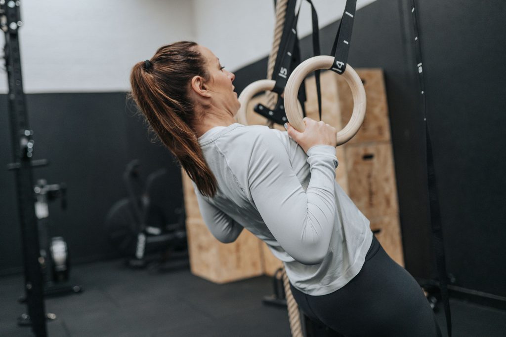 Woman exercising on gymnastic rings in gym
